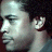 Pixelated profile view of a person with dark hair and light skin, wearing a light-colored shirt against a dark background.