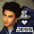 Pixelated image of a person with dark hair wearing a blue jacket over light shirt, next to text reading "I ❤️ JESS" in white and black block letters.