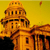 Pixelated image of a domed building with columns against a yellow background, featuring a small flag-like shape in the upper right.