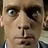Static pixelated image of a person's face with light skin tone, visible eye and nose details, dark hair on the right side, and partial clothing in blue and white tones.