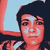 A pixelated image of a person with dark hair and light skin, wearing a striped top against a blue background.