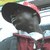 A person wearing a red and white cap, dark jacket with red accents, and silver chain necklace appears in four showing head movement