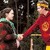 Two pixelated figures stand side-by-side against a dark background, with one figure in red clothing holding hands with another figure in brown and green attire.