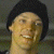 A pixelated image of a person with dark hair and light skin smiling, next to green text reading 'Original Icons .com' on a solid background.
