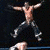 Animated sequence showing a shirtless man in dark pants performing a wrestling move, followed by two wrestlers grappling on the mat.