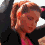 A four- shows a person with light brown hair in a ponytail wearing a black jacket over a pink top, with subtle head and shoulder movements