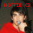 Pixelated image of a person in a red shirt holding a microphone, with red text reading 'HOTTIE <3' above the head against a dark background.