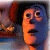 Pixelated cartoon-style face with orange skin, blue accents, and black hair, set against a blurred background with red and blue tones.