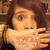 A person with brown hair covers their mouth with a hand, showing visible text on the palm in three