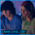 Two pixelated figures in blue and green clothing stand side-by-side against a purple background with three teal rectangular shapes at the bottom.