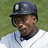 Pixelated image of a person wearing a dark helmet with a white emblem, light blue and white striped shirt, and dark collar, set against a green background.