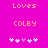 Pixelated text 'Loves COLBY' above five heart symbols on a bright pink background, with one central heart in purple and four light blue hearts.