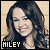 Pixelated portrait of a smiling person with long dark hair against light background, text 'HILEY' in white block letters on black rectangle at bottom left.