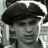 Pixelated grayscale image of a person wearing a dark tricorn hat, with visible facial features including eyes, nose, and mouth, set against a light background.