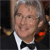 A pixelated close-up of a person in formal attire with a white shirt, black bow tie, and dark jacket, set against a blurred background with warm and cool tones.