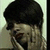 A person with short dark hair holds a phone to their ear, smiling while turning the head slightly left then right
