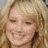 A pixelated image of a smiling person with long blonde hair next to a red heart symbol on white background.