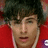 Pixelated close-up of a person with dark hair and light skin wearing a red garment against a red background.