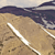 A pixelated landscape with a sandy foreground, dark blue water, and light sky, featuring two white diagonal lines crossing the sand.
