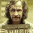 Pixelated image of a person with long hair and mustache, wearing a patterned garment against a light background, accompanied by pixelated text on black