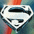 A pixelated image shows a large silver 'S' shield on the left and a Superman figure on the right with a red cape, blue suit, and red 'S' emblem against a black background with white stars.