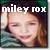 Pixelated static image of a person with closed eyes and a slight smile, overlaid with white text reading 'miley rox' against a dark background.