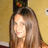 A pixelated image of a person with long brown hair against a beige background, overlaid with red pixelated text on a black background.