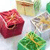 Pixelated static image of four distinct objects: a red cube with a dark opening, a beige cylindrical container, a metallic bowl, and a green leafy item.