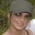 A pixelated close-up of a person wearing a gray cap and dark sunglasses, with a blurred green background.