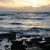Pixelated static image of a sunset over water with dark landmasses in the foreground, showing horizontal bands of blue, gray, and yellow tones.