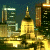 Pixelated cityscape at night with illuminated skyscrapers and a green background displaying 'OriginalIcons.com' in bright green text.