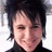 Pixelated close-up of a person with dark hair and light skin, wearing a black top against a white background.