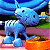 A pixelated animated contact sheet showing two frames of a blue cartoon character with large ears and orange feet against a green background with "Original Icons .com" text.
