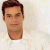 Pixelated static image of a person's head and shoulders in a white shirt against a light background.