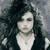 Pixelated static image of a person with long dark hair, light skin, and a white top against a muted gray background.