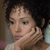 Static 50x50 pixel icon showing a close-up of a person with dark curly hair resting their hand on their cheek, wearing a light-colored top against a blurred background.