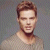 Static pixelated image of a person's upper body with short brown hair and light skin, wearing a neutral-toned shirt against a gray background.