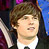 Pixelated close-up of a person with brown hair wearing a white shirt and dark jacket against blurred purple and blue background.
