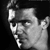 Black-and-white pixelated static image of a person's face in profile view with visible facial features and hair, rendered at low resolution on a dark background.