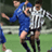 Static 48x48 pixel icon showing two soccer players in mid-action on a green field, one in blue jersey and the other in white striped jersey with black shorts.