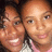 Two people with light brown skin tones smiling closely together in a pixelated static image with warm color tones.