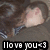 A pixelated image of a person with long brown hair wearing a dark gray shirt, showing text "I love you <3" in white letters on black background.