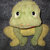 Pixelated yellow-green cartoon character with large black eyes, small mouth, and rounded limbs against dark gray background.