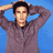 A person in a gray zip-up jacket with hands behind head against blue background, showing two distinct facial expressions across frames.