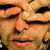 Pixelated close-up of a person's face showing eyes, nose, and mouth with warm skin tones and dark eyebrows.