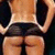 A person viewed from behind wearing a white crop top and black shorts, with hands on hips against a dark background.
