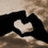 A pixelated static image shows a white heart shape centered on a black background with brown and beige tones surrounding it.