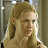Pixelated static image of a person with light brown hair tied back, wearing a light-colored top, against a blurred background with vertical elements.