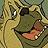 Pixelated cartoon character with large eyes, green body, and orange mouth-like shape on a beige background.