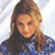 Pixelated image of a person with long brown hair wearing a blue top against a light background.
